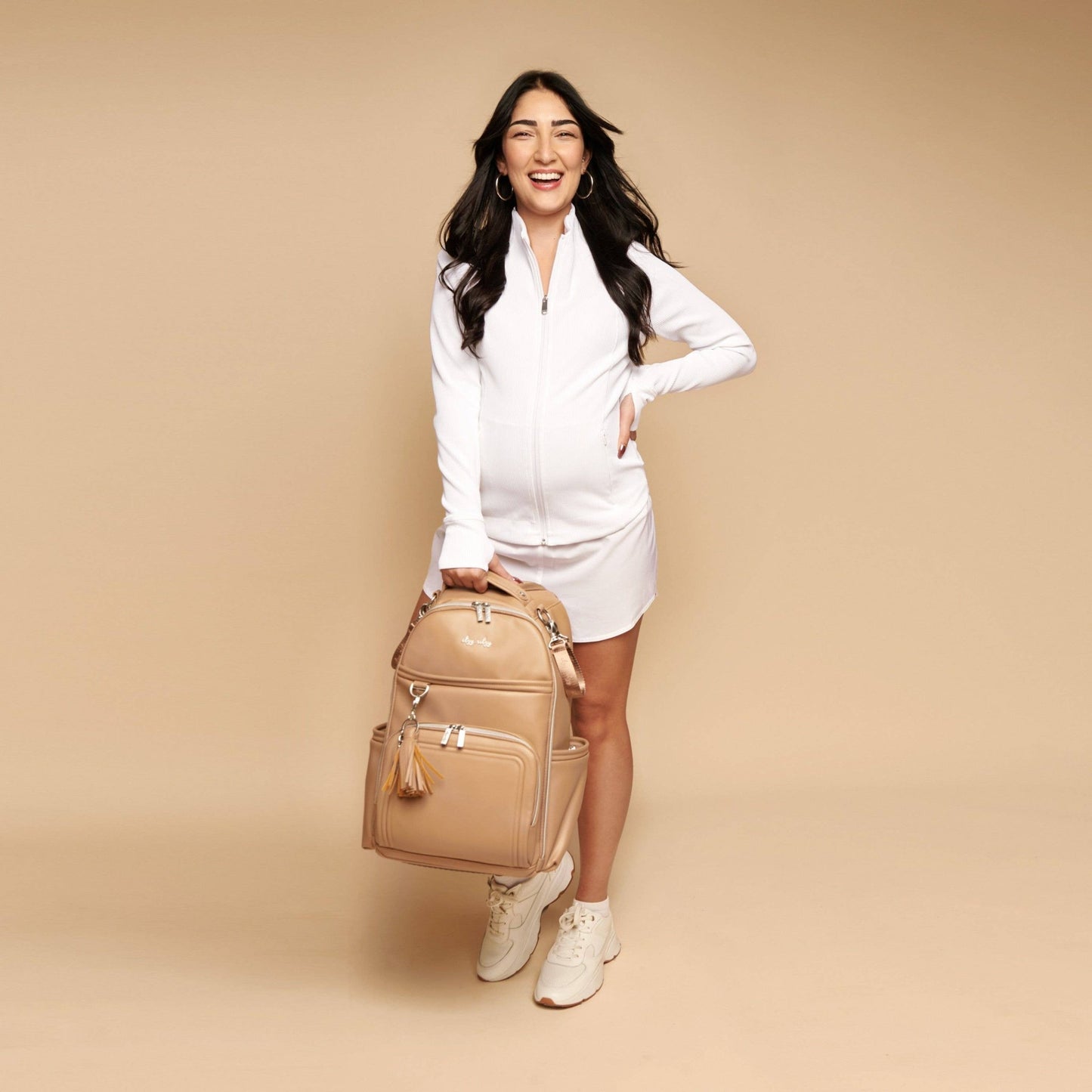 a woman in a white dress holding a tan purse