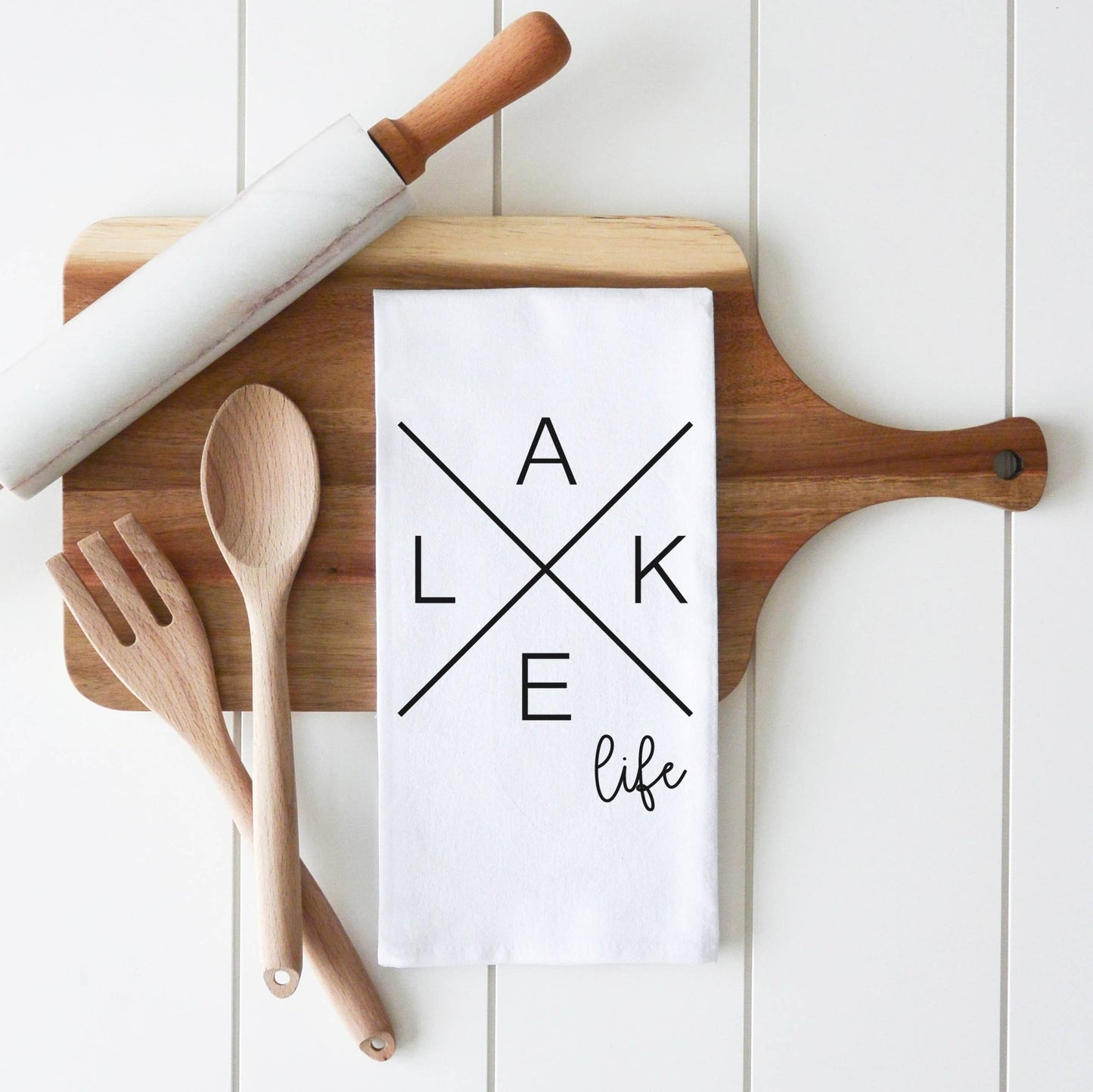 a wooden cutting board with a tea towel and wooden utensils