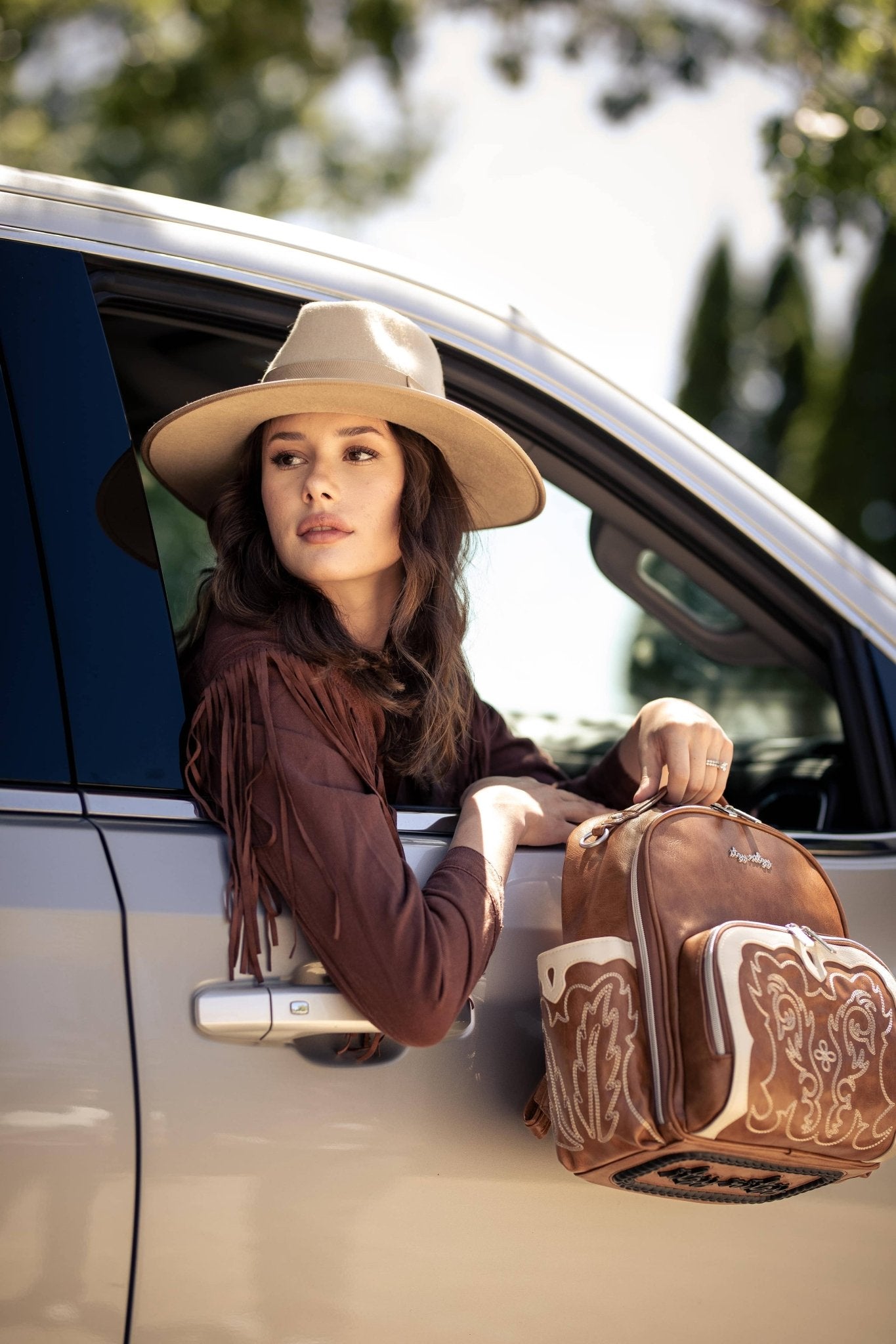 a woman in a cowboy hat leaning out of a car window