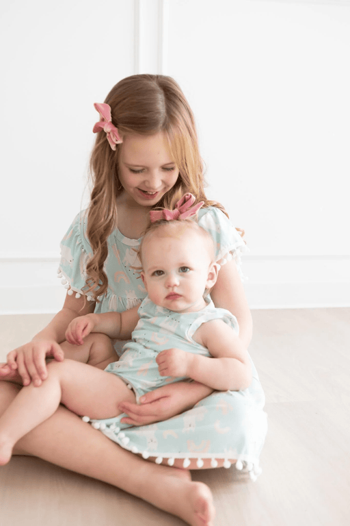 a little girl sitting on the floor holding a baby