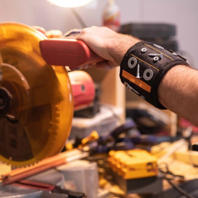 a man is working on a machine in a workshop wearing a magnetic wristband cuff with screws and washers on it