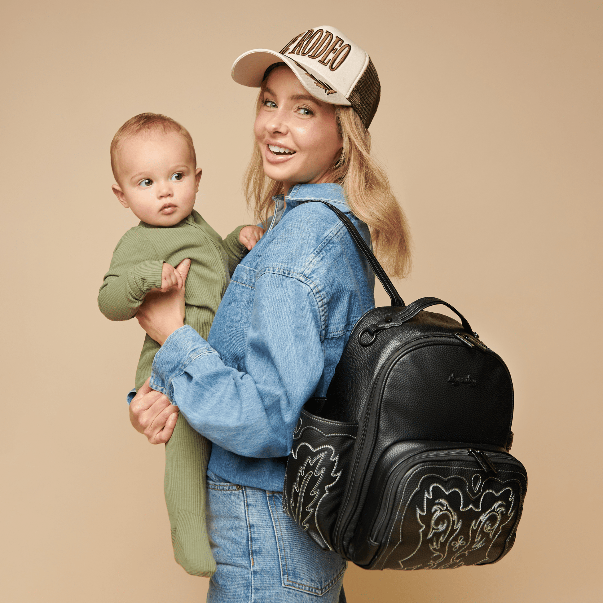 a woman holding a baby and an Itzy Ritzy Nash Outlaw Itzy Mini Plus