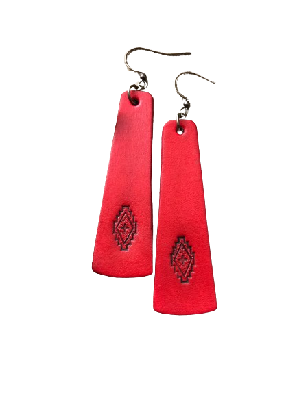 a pair of red earrings with a design on it