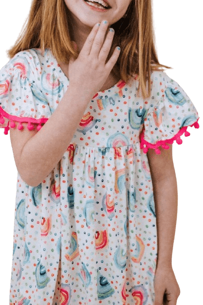 a little girl in a white dress holding her hand up to her mouth