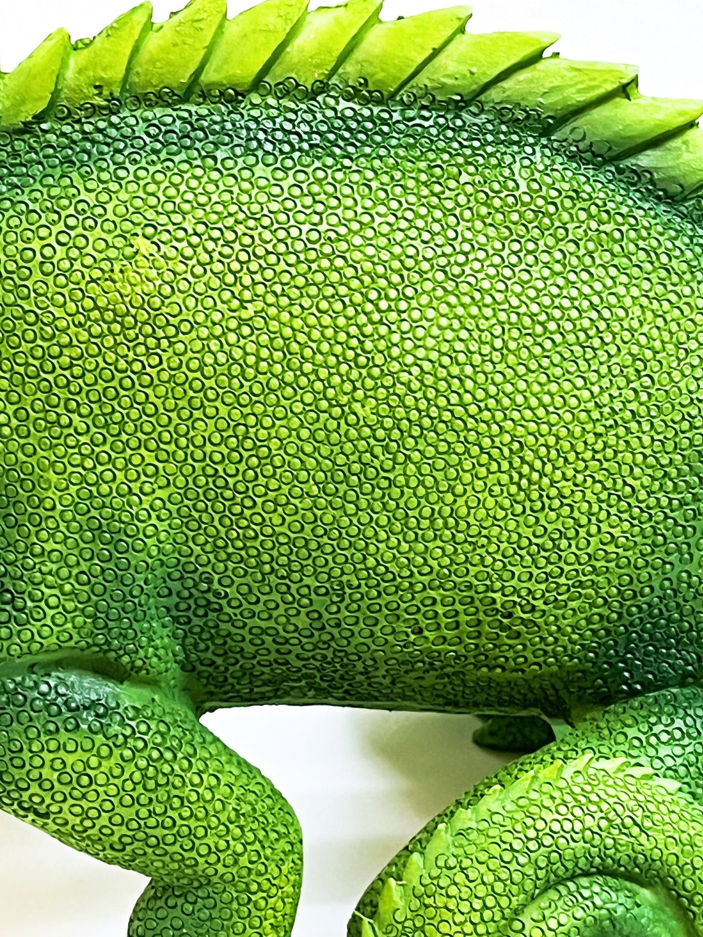 a green toy chamelon sitting on a white surface