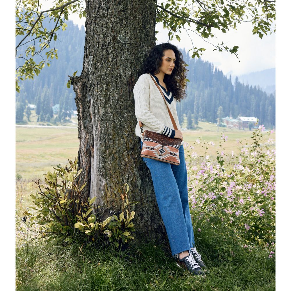 a woman leaning against a tree in a field