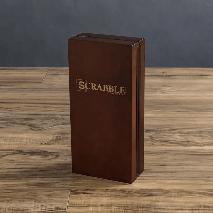 a brown travel scrabble board game sitting on top of a wooden table