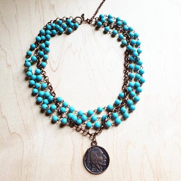 a turquoise beaded necklace with a coin on it