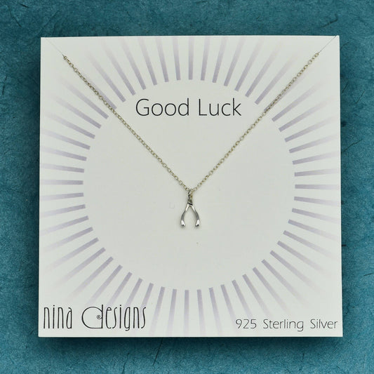 a card with a sterling silver wishbone necklace on it that says good luck