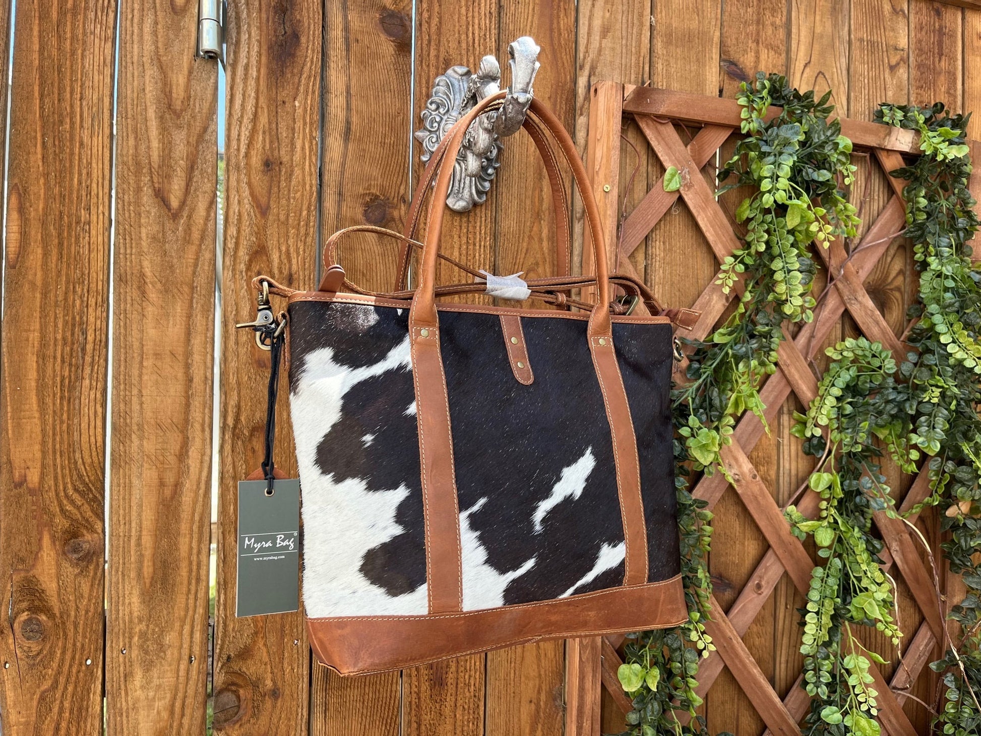 a cow hide purse hanging on a wooden fence