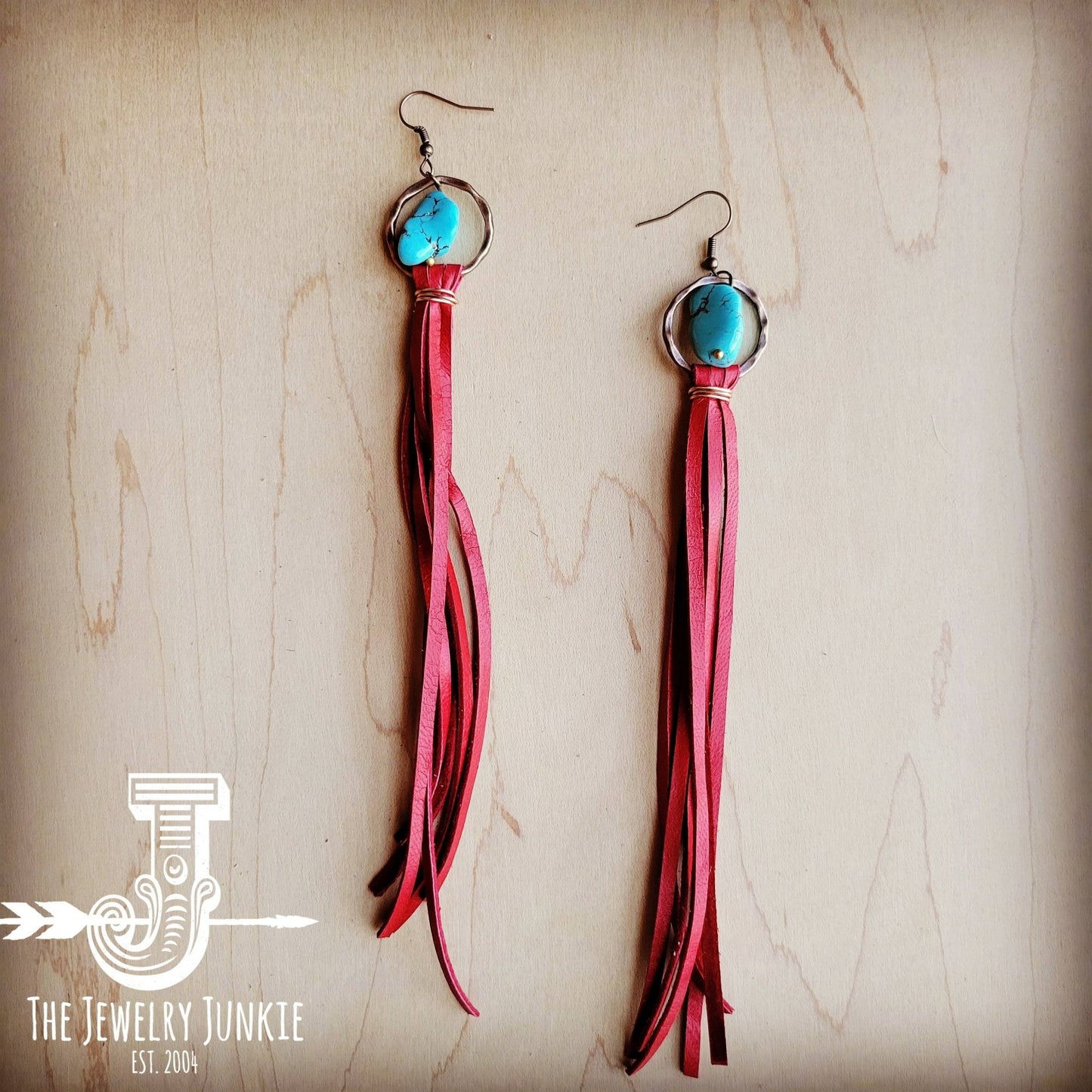 a pair of red tasselled earrings with turquoise beads