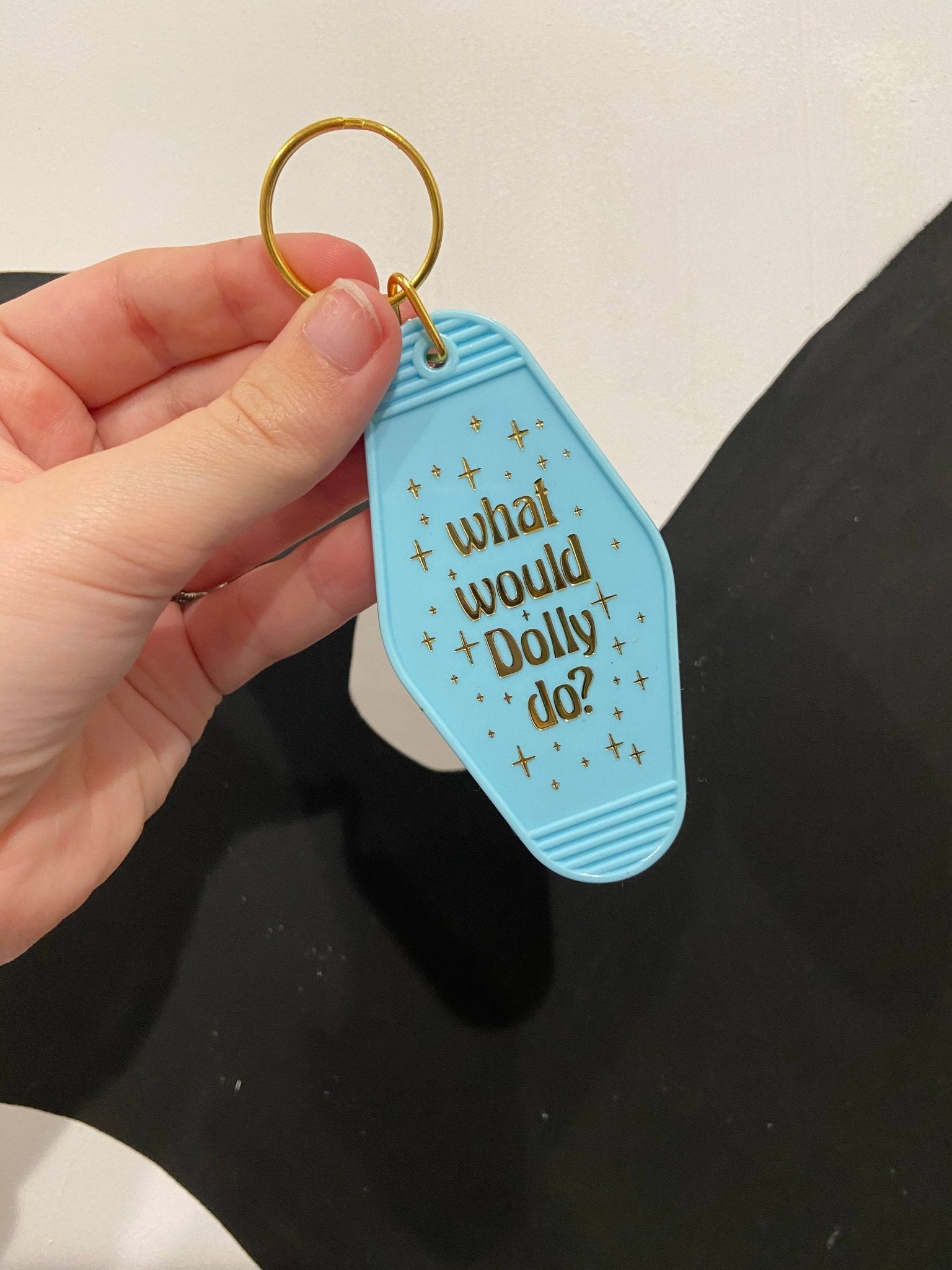 a hand holding a blue keychain with what would dolly do written on it