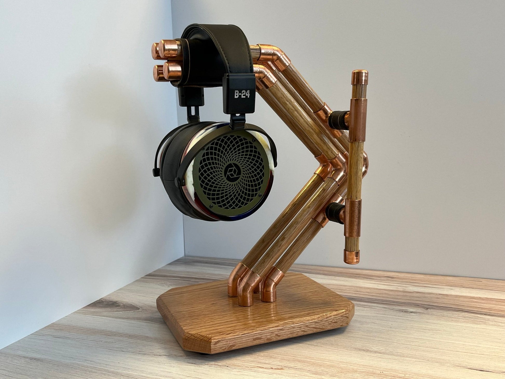 a headphone stand made out of copper pipes and wood and headphones on it