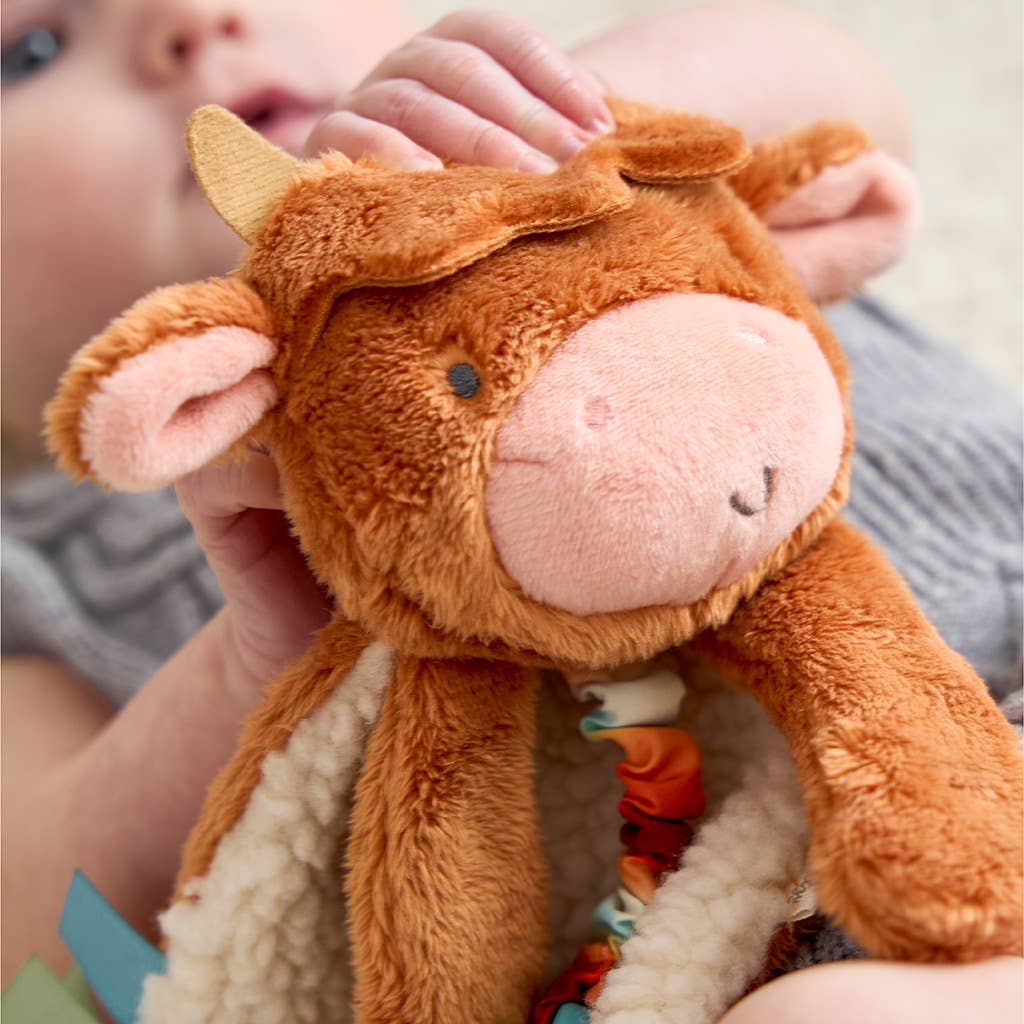 a baby is holding a stuffed cow toy