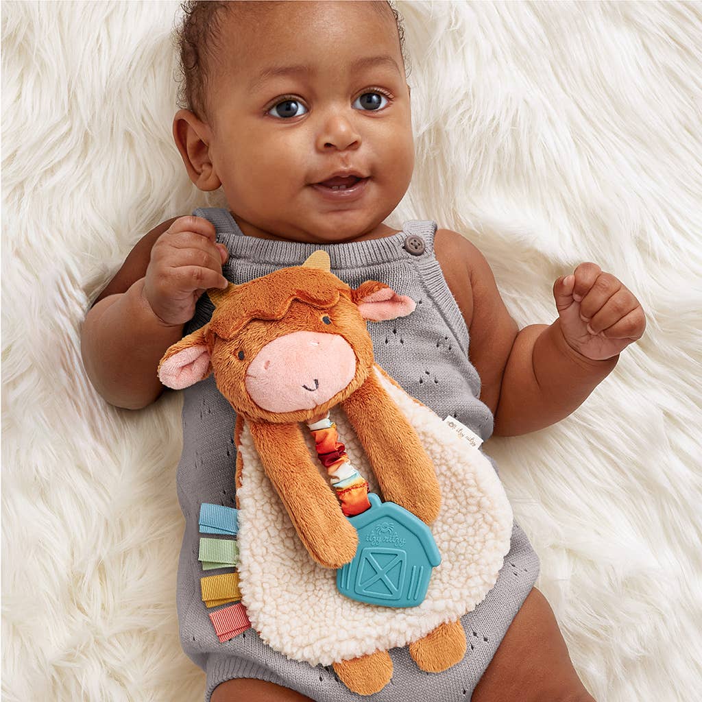 a baby laying on a white rug holding a stuffed animal