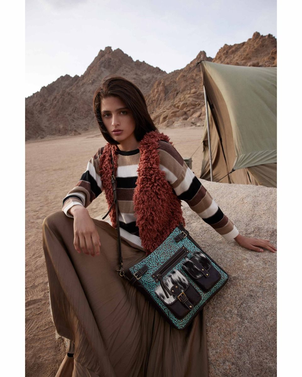 a woman sitting on a rock with a handbag