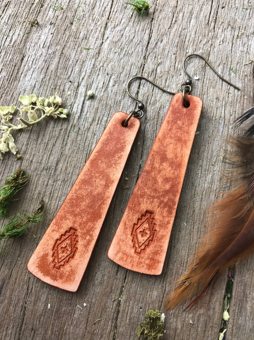 a pair of leather earrings on a table