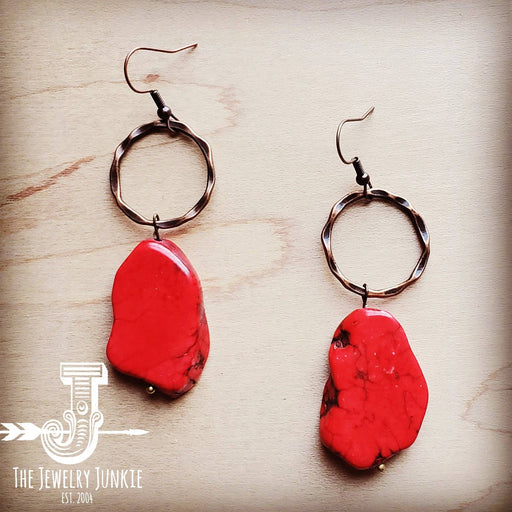 a pair of earrings with a red stone hanging from it