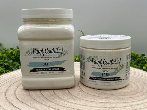 two jars of paint couture satin topcoat sitting on top of a wooden table