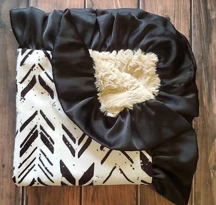 a black and white baby blanket on a wooden floor