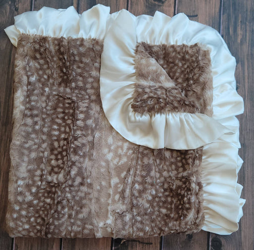 a brown and white doe print fur baby blanket on a wooden floor