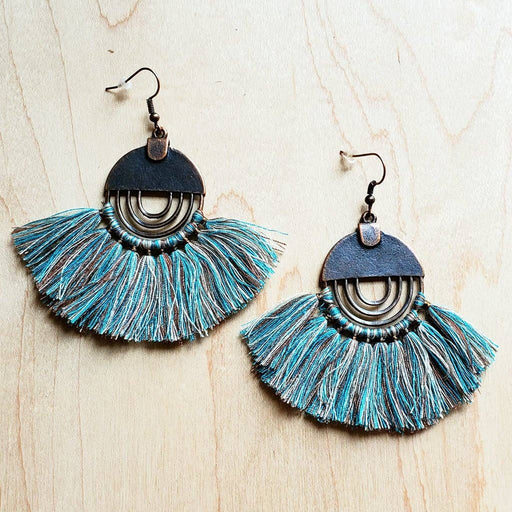 a pair of blue and black earrings on a wooden surface