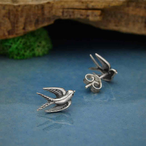 a pair of swallow bird earrings sitting on top of a table