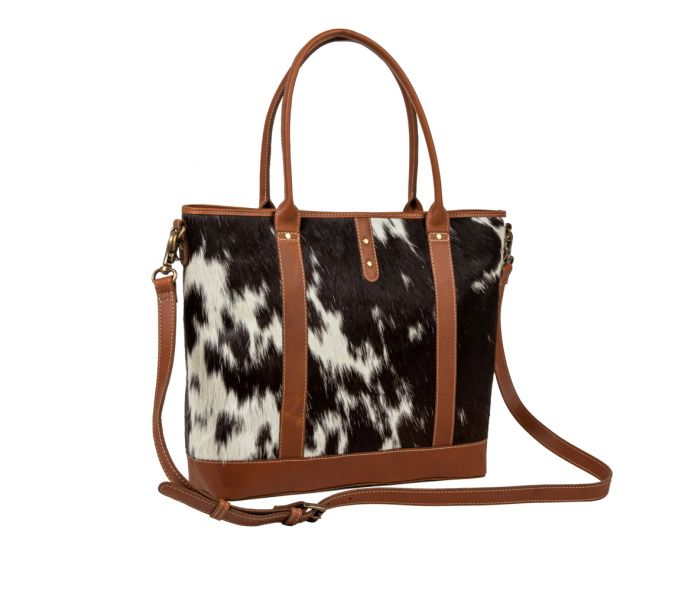 a black and white cow print purse with brown straps