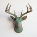 a copper and green patina deer head mounted on a wall