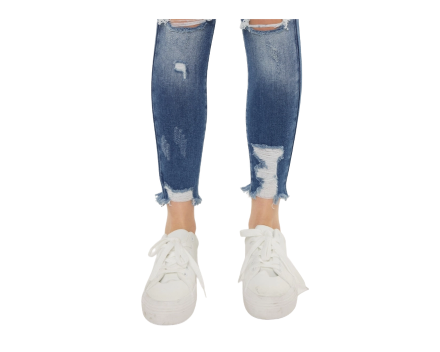 a woman's legs in ripped jeans and white sneakers