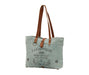 a blueish-gray tote bag with a brown leather handle on a white background