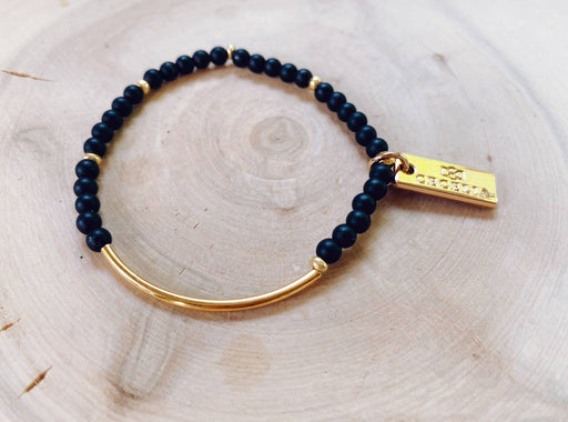 a black beaded gemstone bracelet with a gold bar