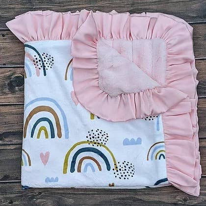 a baby blanket with a pink ruffle on top of it