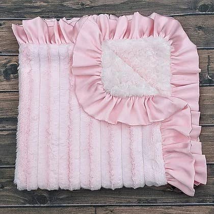 a pink baby blanket with ruffled edges on a wooden floor